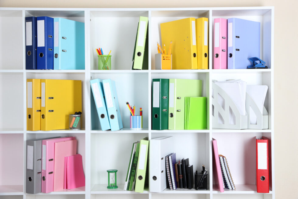 White office shelves with folders and different stationery, close up