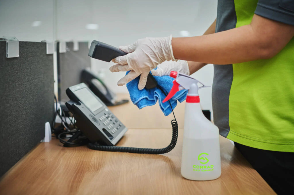 a cleaner cleaning the phone handle in office